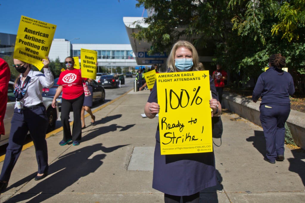 Megan Robinson holds up a yellow sign at a protest outside PHL Airport
