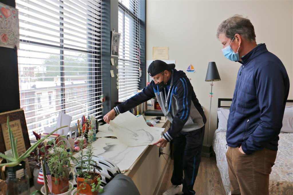 Luis Lozada shows his artwork to Chris Maguire