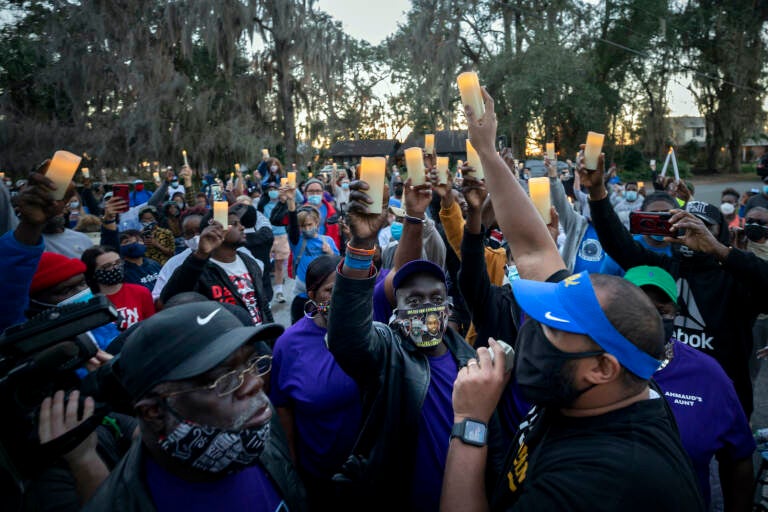 Ahmaud Arbery's father, Marcus Arbery, bottom center, listens to Jason Vaughn speak during a memorial walk and candlelight vigil