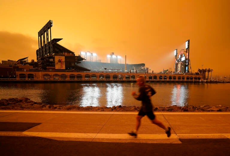 A jogger runs along McCovey Cove outside Oracle Park, under darkened skies from wildfire smoke