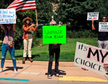Protesters hold signs denouncing vaccine and mask mandates