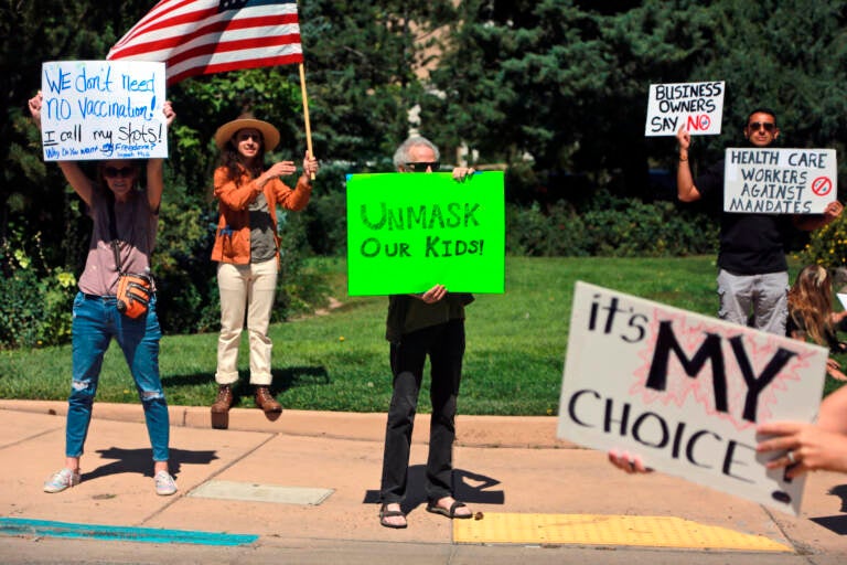 Protesters hold signs denouncing vaccine and mask mandates