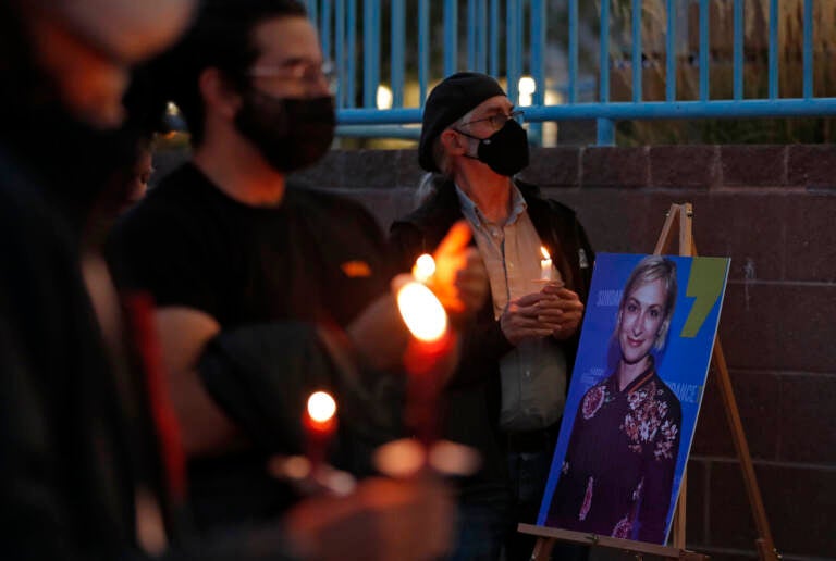Mourners, wearing face masks, are pictured holding candles at a vigil for Halyna Hutchins