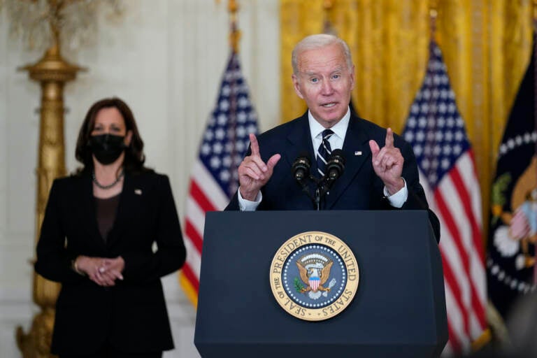 President Joe Biden speaks from a podium, with VP Kamala Harris in the background
