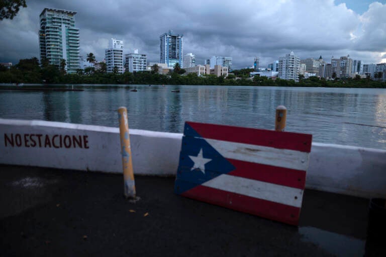A wooden Puerto Rican flag lies on the shore of the Condado lagoon, where multiple selective blackouts have been recorded in the past days, in San Juan, Puerto Rico, Thursday, Sept. 30, 2021. Power outages across the island have surged in recent weeks, with some lasting up to several days. (AP Photo/Carlos Giusti) 