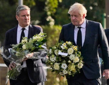 British Prime Minister Boris Johnson, right, and Leader of the Labour Party Keir Starmer carry flowers as they arrive at the scene where a member of Parliament was stabbed Friday, in Leigh-on-Sea, Essex, England, Saturday, Oct. 16, 2021