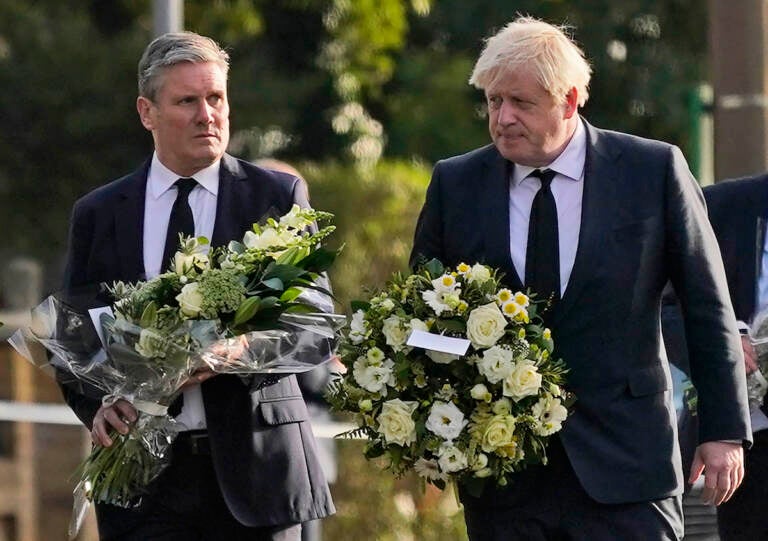 British Prime Minister Boris Johnson, right, and Leader of the Labour Party Keir Starmer carry flowers as they arrive at the scene where a member of Parliament was stabbed Friday, in Leigh-on-Sea, Essex, England, Saturday, Oct. 16, 2021