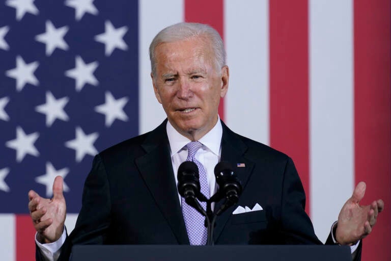 President Joe Biden speaks in front of an American flag backdrop