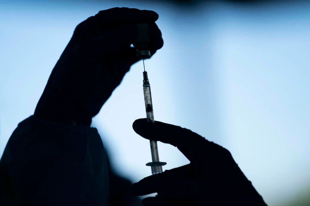 Hands are pictured preparing a COVID-19 vaccine