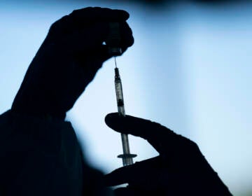 Hands are pictured preparing a COVID-19 vaccine