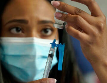 A nurse draws a Moderna COVID-19 vaccine into a syringe