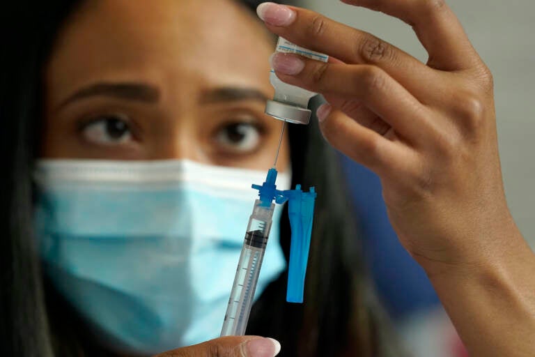 A nurse draws a Moderna COVID-19 vaccine into a syringe