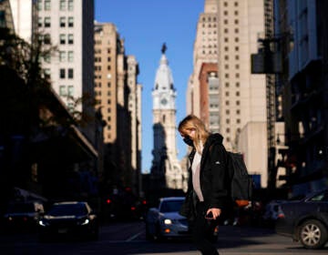 A woman wearing a face mask crosses Broad Street