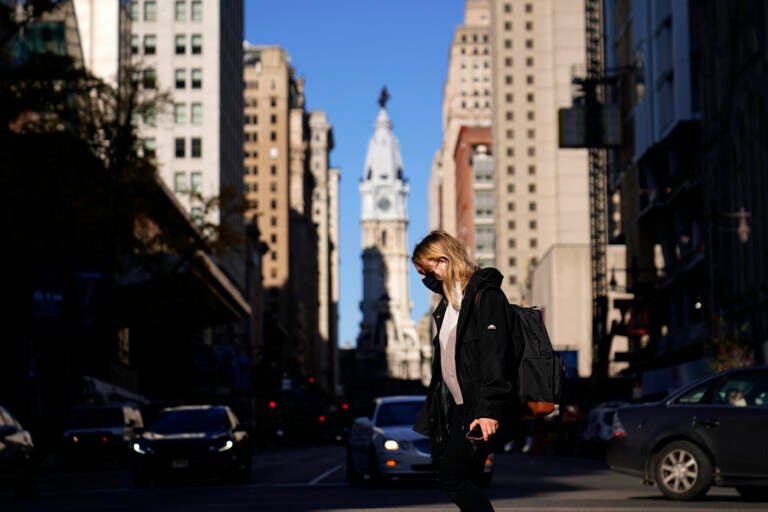 A woman wearing a face mask crosses Broad Street