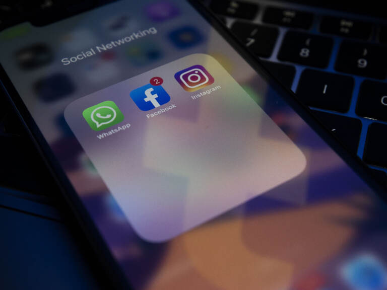 A photo illustration shows social media apps Instagram, Facebook, and WhatsApp on a phone screen