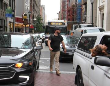 A pedestrian threads his way through snarled traffic