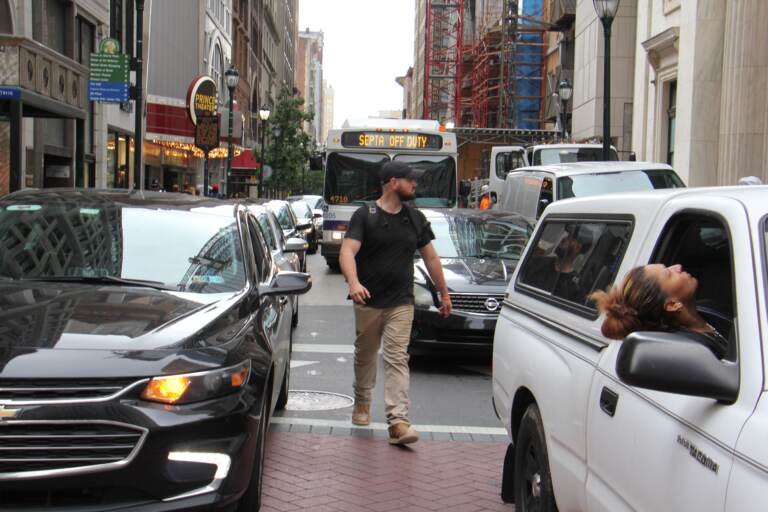 A pedestrian threads his way through snarled traffic