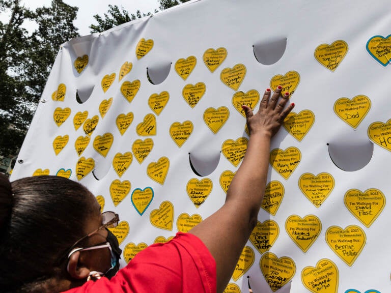 A person places a sticker representing a lost relative on a tribuet wall