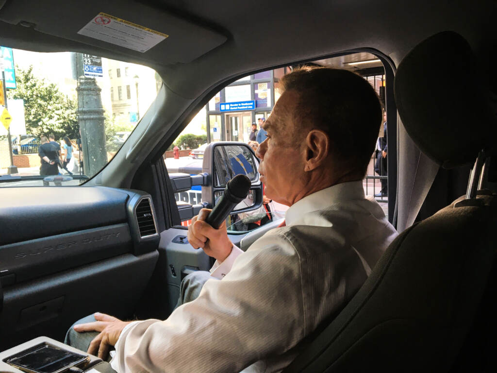 Chuck Peruto is pictured inside his truck holding a microphone