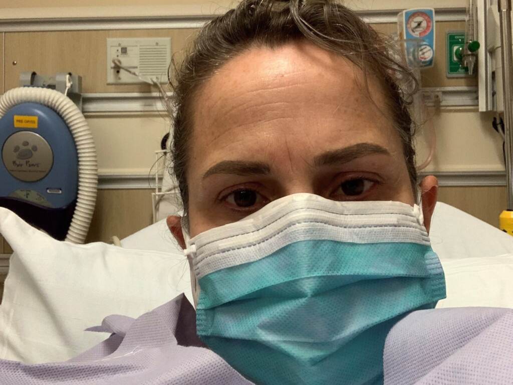 Chelsea Titus is pictured wearing a mask in a hospital bed.