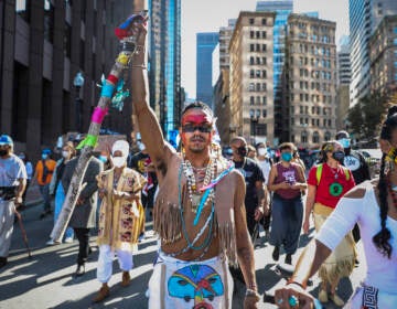 A demonstrator marches to Faneuil Hall with other protesters while participating in the Indigenous Peoples Day rally and march in Boston on Oct. 10, 2020. (Photo by Erin Clark/The Boston Globe via Getty Images)