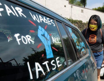 Crystal Kan, a storyboard artist, draws signs on cars of IATSE union members during a rally in Los Angeles in September. (Myung J. Chun/Getty Images)