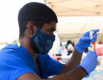 A health care worker prepares a dose of the Moderna COVID-19 vaccine during a clinic held at the Watts Juneteenth Street Fair in the Watts neighborhood of Los Angeles. (Patrick T. Fallon/AFP via Getty Images)