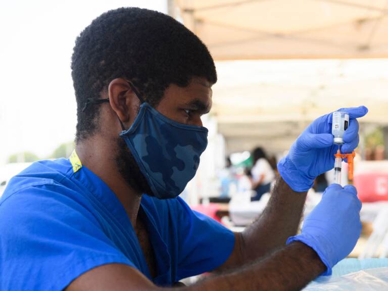 A health care worker prepares a dose of the Moderna COVID-19 vaccine during a clinic held at the Watts Juneteenth Street Fair in the Watts neighborhood of Los Angeles. (Patrick T. Fallon/AFP via Getty Images)