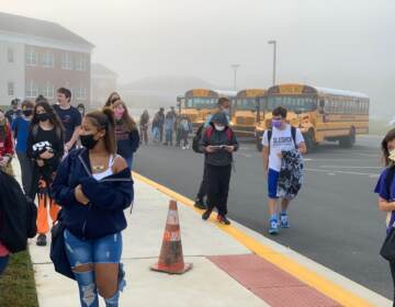 Students, wearing masks, walk into school