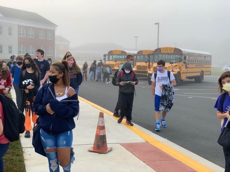 Students, wearing masks, walk into school