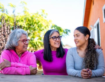 Three generations, (from left to right) grandmother Genoveva Calloway, daughter Petra Gonzales, and granddaughter Vanesa Quintero sit together in their shared backyard in San Pablo on Nov. 3, 2021. (Beth LaBerge/KQED)