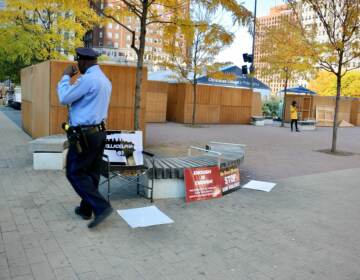A Philadelphia police officer walks past the scene of a shooting in LOVE Park. A 29-year-old man was killed. A security guard for Christmas Village has been charged