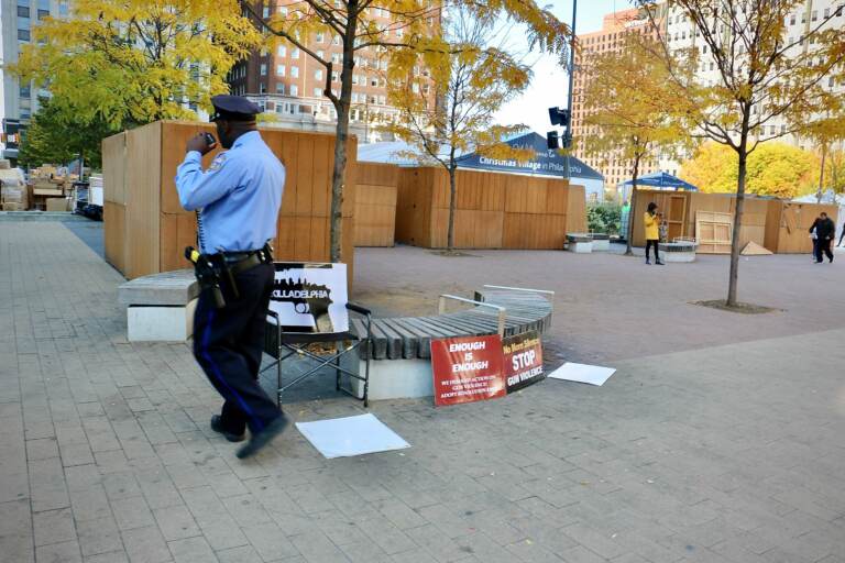 A Philadelphia police officer walks past the scene of a shooting in LOVE Park. A 29-year-old man was killed. A security guard for Christmas Village has been charged