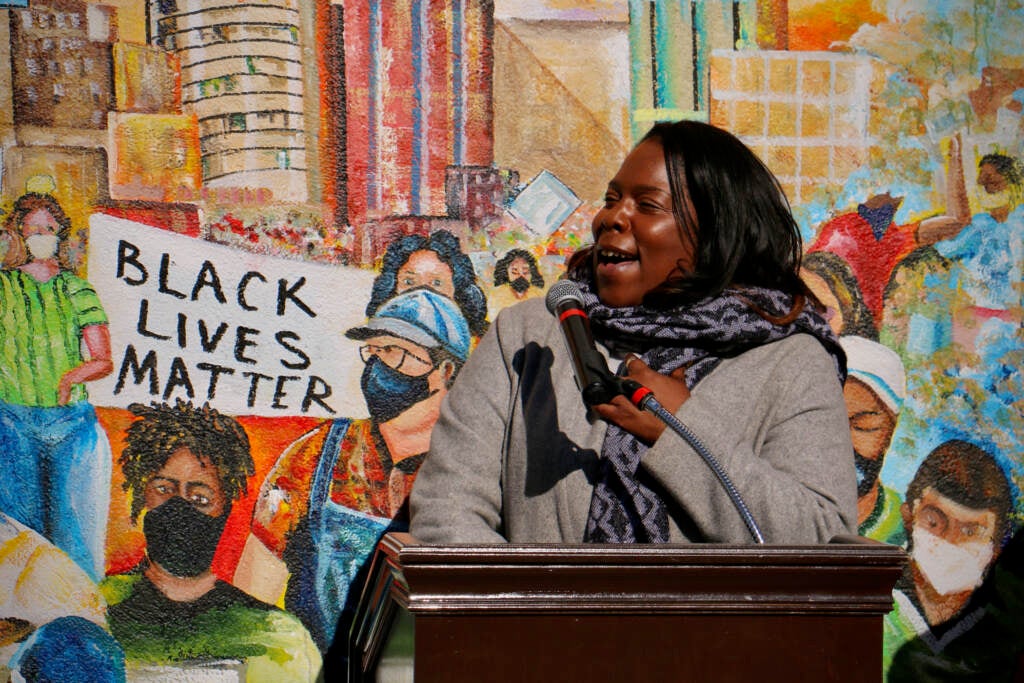 Stephanie Michel speaks from a podium at a mural unveiling