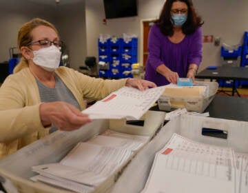 Board worker Ann Carlette, left, process and double-check mail-in ballots