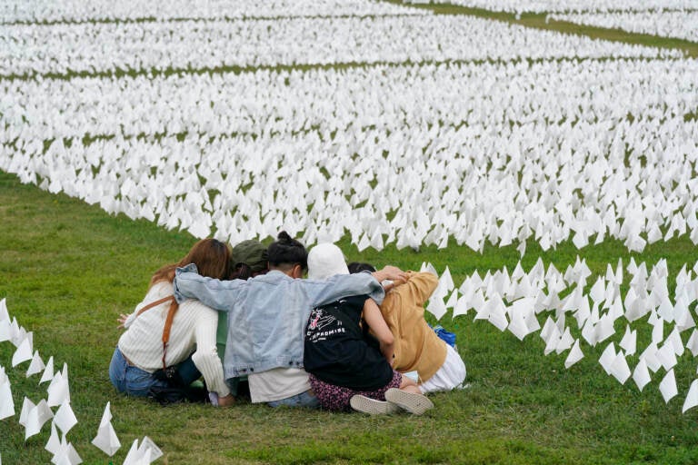 Visitors sit among white flags that are part of artist Suzanne Brennan Firstenberg's 