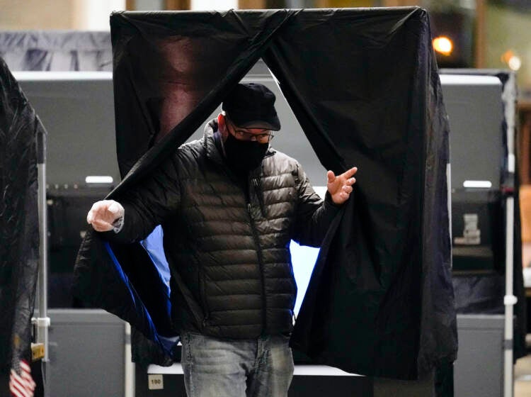 A voter wearing a face mask exists from the voting booth