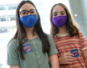 Ryann and Jamie Onofrio Franceschini pose for a photo with COVID-19 vaccine stickers while wearing face masks