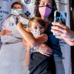 Finn Washburn shows his vaccination site as mom Kate Elsley takes a photo