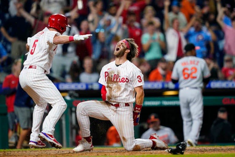 Philadelphia Phillies' Bryce Harper (3) and Andrew Knapp (5) celebrate after Harper scored the game-winning run on a two-run triple by J.T. Realmuto during the 10th inning of an interleague baseball game against the Baltimore Orioles, Tuesday, Sept. 21, 2021, in Philadelphia