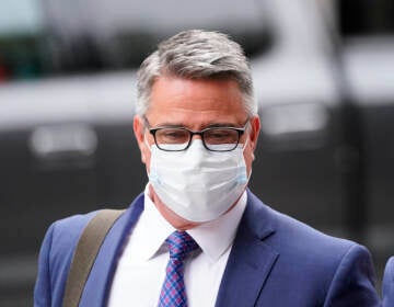 Bobby Henon walks while wearing a face mask