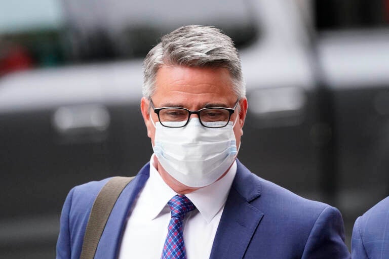 Bobby Henon walks while wearing a face mask