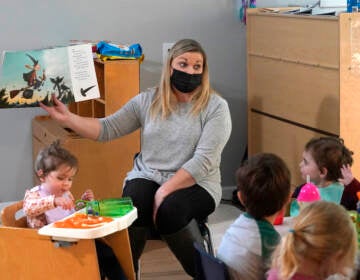 Amy McCoy reads a book to preschoolers as they finish their lunch at her Forever Young Daycare facility, Monday, Oct. 25, 2021, in Mountlake Terrace, Wash. (AP Photo/Elaine Thompson)
