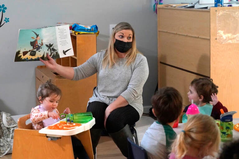 Amy McCoy reads a book to preschoolers as they finish their lunch at her Forever Young Daycare facility, Monday, Oct. 25, 2021, in Mountlake Terrace, Wash. (AP Photo/Elaine Thompson)