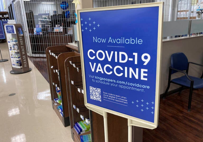 A sign notifies customers that COVID-19 vaccinations are available at a pharmacy in a grocery store