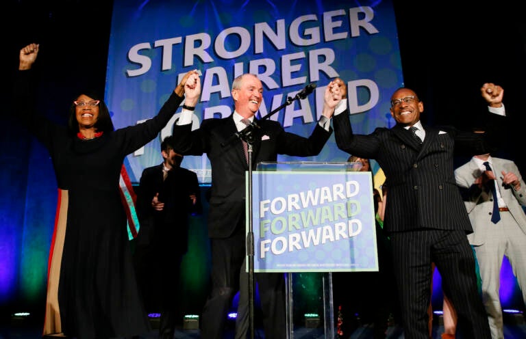 Lt. Gov. Sheila Oliver, left, New Jersey Gov. Phil Murphy, center, and LeRoy Jones, chairman of the state's Democratic committee, right, celebrate at Convention Hall after Murphy won the gubernatorial race against Jack Ciattarelli, Wednesday, Nov. 3, 2021, in Asbury Park, N.J. (AP Photo/Noah K. Murray)