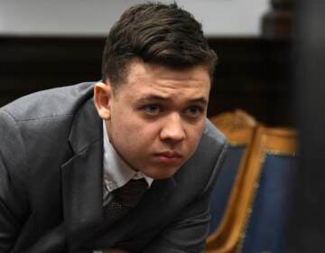 Kyle Rittenhouse peers at the screen as attorneys for both sides argue about a video during Rittenhouse's trial at the Kenosha County Courthouse in Kenosha, Wis., on Friday, Nov. 12, 2021. Rittenhouse is accused of killing two people and wounding a third during a protest over police brutality in Kenosha, last year. (Mark Hertzberg /Pool Photo via AP)