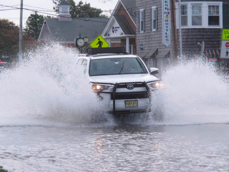 This Oct. 11, 2019 photo shows a car kicking up spray while driving through a flooded street in Bay Head, N.J. Bay Head is moving forward with its own proposed solutions to back bay flooding in response to 