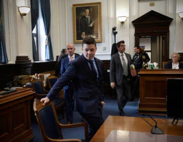 Kyle Rittenhouse, center, pulls out his chair for a meeting Judge Bruce Schroeder called during his trial at the Kenosha County Courthouse in Kenosha, Wis., on Thursday, Nov. 18, 2021