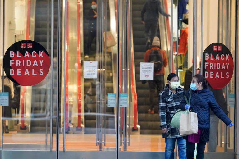 Black Friday shoppers wear face masks and gloves as the leave the Uniqlo store along Fifth Avenue, Friday, Nov. 27, 2020, in New York